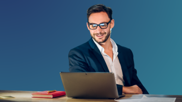 Businessman sitting at desk looking happily at laptop