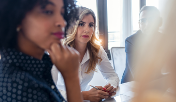 Business people meeting, listening to speaker, one businesswoman looking pensive